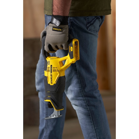 Photo of STANLEY SFMCS300M1K cordless reciprocating saw in yellow and black, held by a person wearing work gloves.