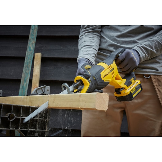 STANLEY SFMCS300M1K reciprocating saw cutting wood, close-up view, yellow and black cordless tool.