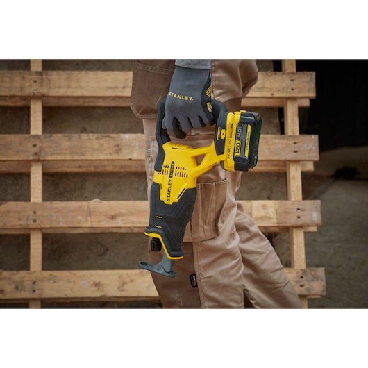 STANLEY SFMCS300M1K cordless reciprocating saw held by worker, yellow and black design.