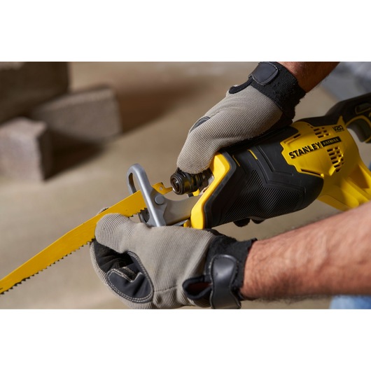 STANLEY SFMCS300M1K reciprocating saw close-up, yellow and black, gloved hands adjusting blade.