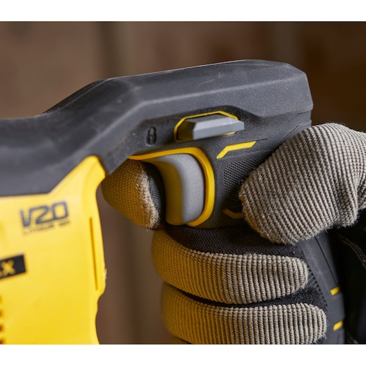 Close-up of STANLEY SFMCS300M1K power tool handle with glove gripping trigger, V20 branding visible.