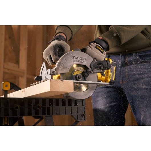 Photo of STANLEY SFMCS500M1K circular saw cutting wood, held by person wearing gloves during woodworking.