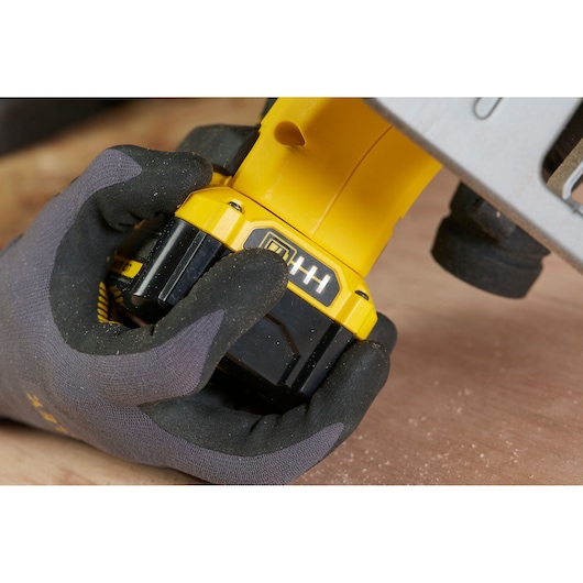 Photo of STANLEY SFMCS500M1K power tool battery being checked by gloved hand, close-up.