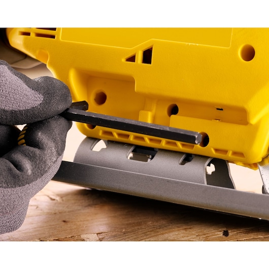 STANLEY SFMCS600M1K jigsaw close-up showing gloved hand using hex key to adjust base plate.