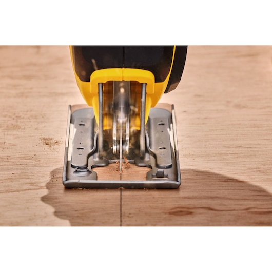 STANLEY SFMCS600M1K jigsaw front view cutting wood, close-up of blade and shoe plate.