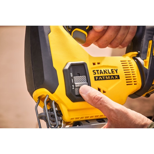 Photo of STANLEY SFMCS600M1K jigsaw close-up, showing a hand adjusting the speed control switch.