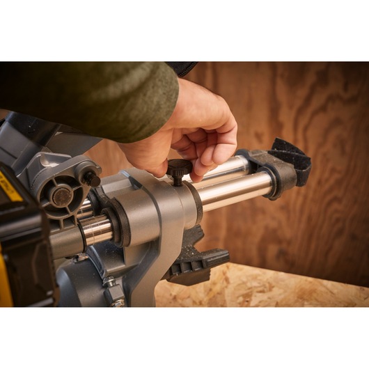 STANLEY SFMCS701M1 miter saw close-up showing user adjusting silver guide rail.