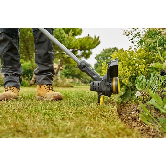 STANLEY SFMCST925M1 grass trimmer in use trimming lawn edge, close-up outdoor view.