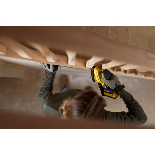 Photo of person using STANLEY SFMCW221B cordless sander on wooden staircase railing.