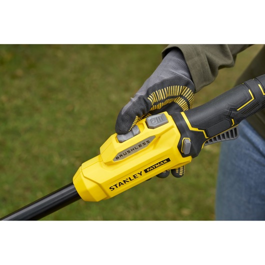 STANLEY SFMSTB930M brushless trimmer handle close-up, yellow and black design, gloved hand holding.