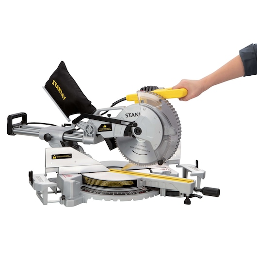 Photo of STANLEY SM18-B2C miter saw with dust bag, side view, a hand holding yellow handle.
