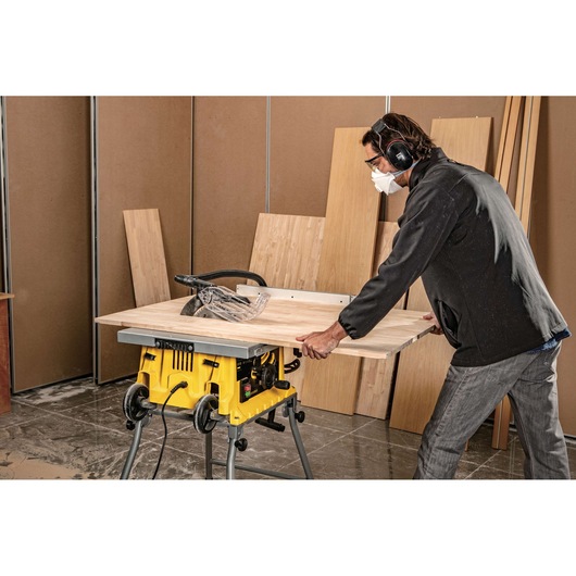 STANLEY SST1800 table saw in use cutting plywood, with user wearing ear protection in a workshop.