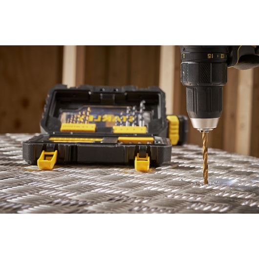 STANLEY STA88550 drill bit set in open black case with yellow latches, with drill bit in use on metal surface, front view.
