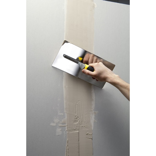 STANLEY STHT0-05900 plastering trowel smoothing wall joint, frontal angle, yellow and black handle.