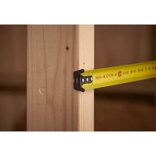 STANLEY STHT0-33561 tape measure in use measuring wooden beam, close-up photography.