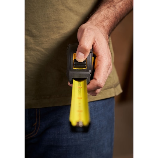 STANLEY STHT0-33561 tape measure held in hand, yellow blade extended, close-up photography.