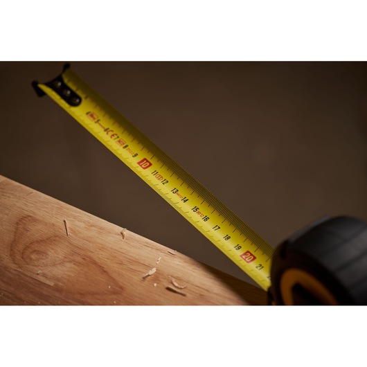 STANLEY STHT0-33566 tape measure close-up on wood, yellow blade with black markings.