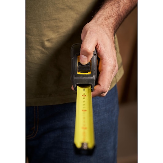 Photo of STANLEY STHT0-33566 tape measure in hand, yellow blade extended, front view.