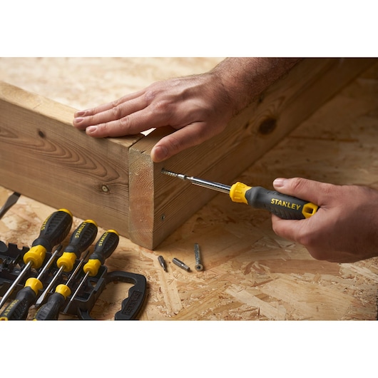 STANLEY STHT0-62144 screwdriver set in use, assembling wooden boards on a workshop table, side angle.
