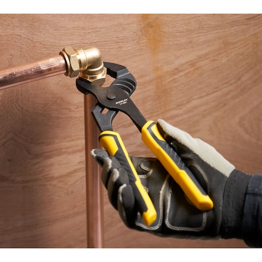 Photo of STANLEY STHT0-74361 slip joint pliers with yellow handles, adjusting copper pipe fitting.