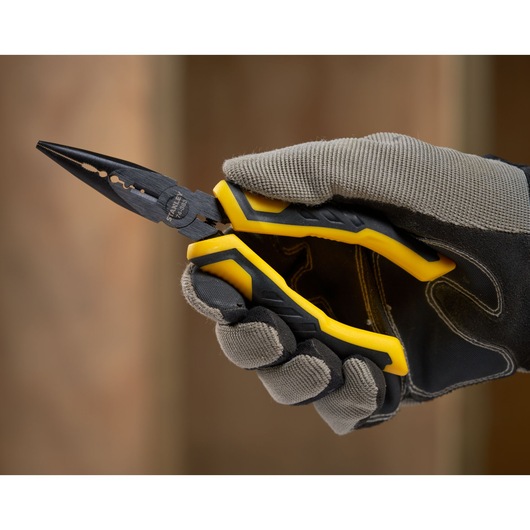 STANLEY STHT0-74363 pliers with yellow and black handles held in a gloved hand, close-up photography.