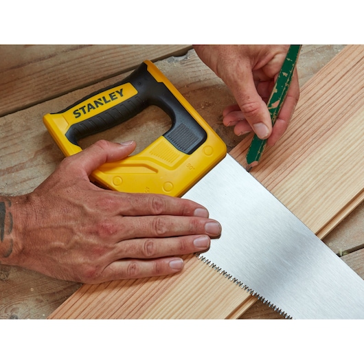 Photo of STANLEY STHT1-20353 handsaw with yellow and black handle cutting a wooden plank.