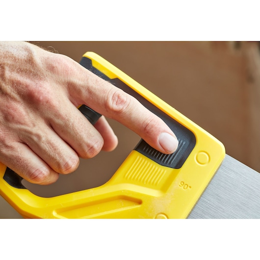STANLEY STHT1-20353 hand saw close-up, yellow handle with black grip, finger on adjustment feature.