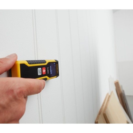 Photo of STANLEY STHT1-77032 laser distance measurer held against a white wall.