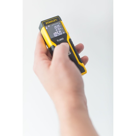 Photo of STANLEY STHT1-77032 laser distance measurer held in hand, display screen visible.