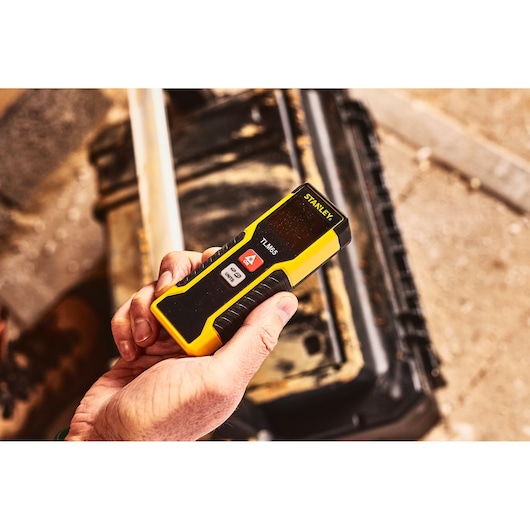 STANLEY STHT1-77032 laser distance measurer held in hand, yellow and black color, photography.