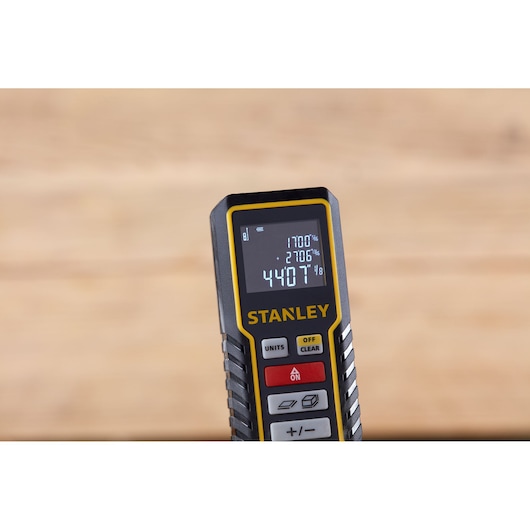 Photo of STANLEY STHT1-77138 laser distance measurer, black and yellow, front angle showing digital display.
