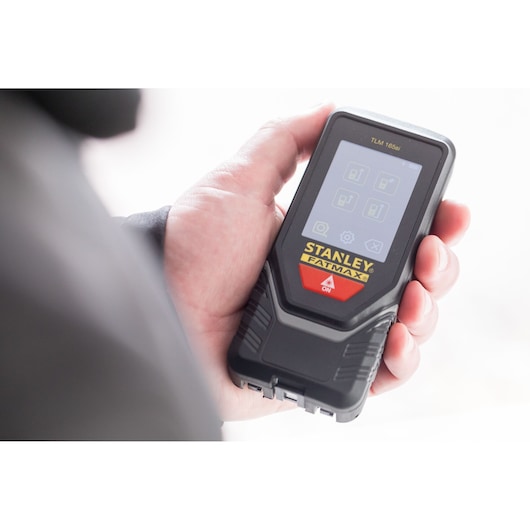 Photo of STANLEY STHT1-77142 laser distance measurer held in hand, black casing, touchscreen display.
