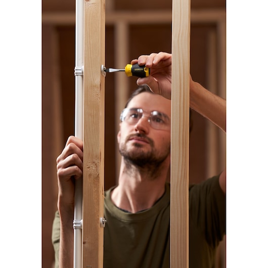 STANLEY STHT16147-0 screwdriver in use tightening a screw on wood framing, product photography.