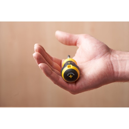 STANLEY STHT16154-0 screwdriver in a hand, yellow and black handle, photography close-up.