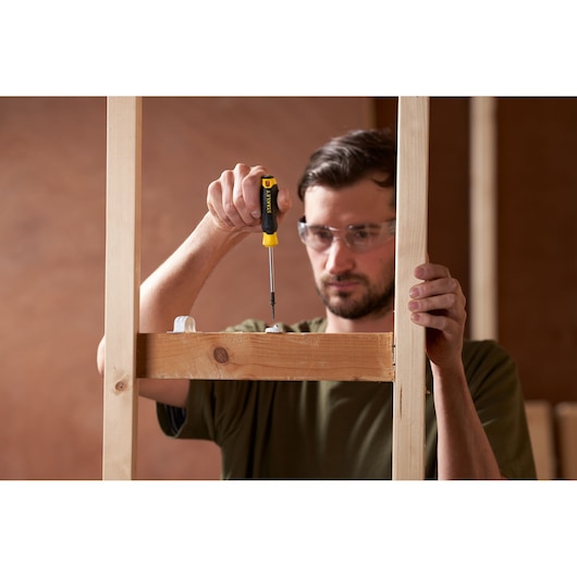 Photo of STANLEY STHT16155-0 screwdriver in use on wood frame construction, close-up view.