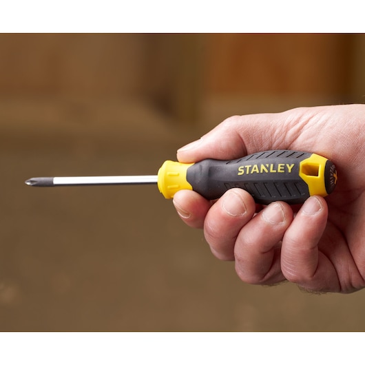 STANLEY STHT16155-0 screwdriver with black and yellow handle held in hand, side view.