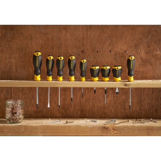 STANLEY STHT16157-0 screwdriver set with black and yellow handles arranged on a wooden shelf.
