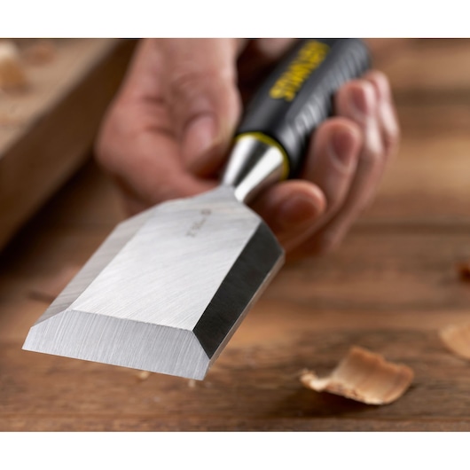 Photo of STANLEY STHT16737-0 wood chisel with sharp blade and black handle in use on wooden surface.