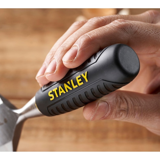 Close-up of STANLEY STHT16737-0 chisel with black and yellow handle held in hand, woodworking tool.