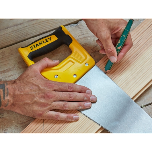 STANLEY STHT20372-1 hand saw with yellow handle on wood, pencil marking cut line, close-up photography.