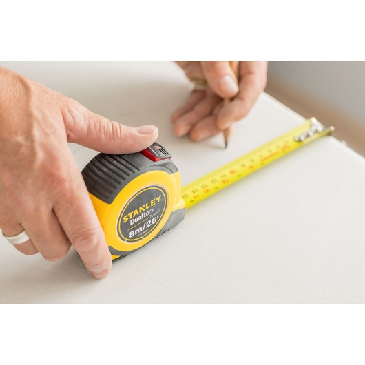 STANLEY STHT36807-0 measuring tape in use, yellow case with black accents, extended on a white surface.