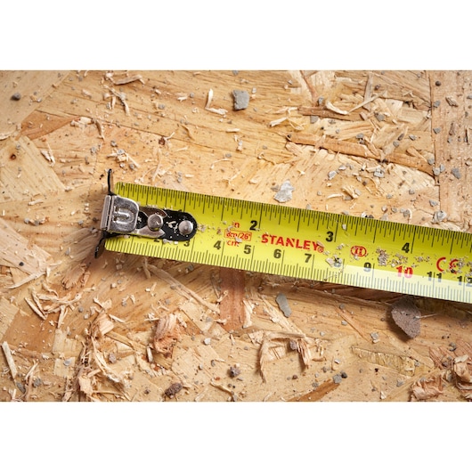 STANLEY STHT37236-5 yellow tape measure extended on plywood, close-up of measurement markings.
