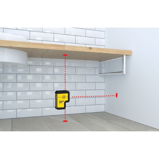 STANLEY STHT77503-1 laser level projecting red lines on wall and floor, shown in a room corner photography.