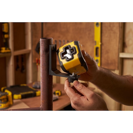STANLEY STHT77611-0 laser level mounted on bracket, hands adjusting in workshop setting.