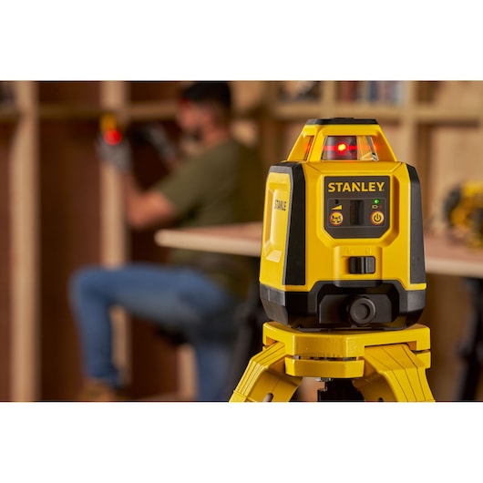 Photo of STANLEY STHT77616-0 laser level on tripod, focused in workshop setting.
