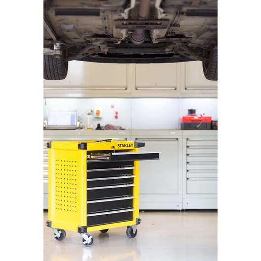 STANLEY STMT1-74306 yellow rolling tool cabinet with open drawer in workshop, side angle.