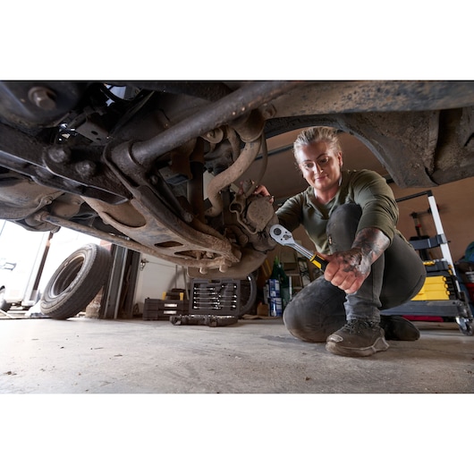 Photo of STANLEY STMT82665-0 1272-ToothRatchet being used under a vehicle in a garage setting.