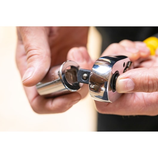 STANLEY STMT82665-0 close-up photo of a ratchet wrench with socket being attached, hand-held, shiny chrome finish.