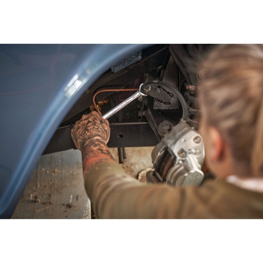 STANLEY STMT82832-1 ratchet wrench in use repairing a car, user holding tool under car wheel well.