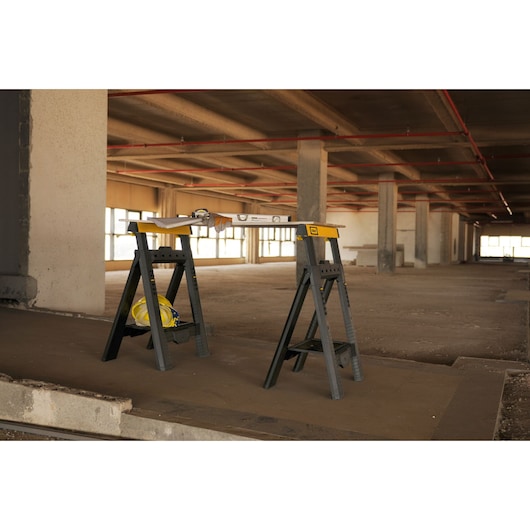 STANLEY STST1-70559 folding sawhorses with tools on top, photographed in a construction site.